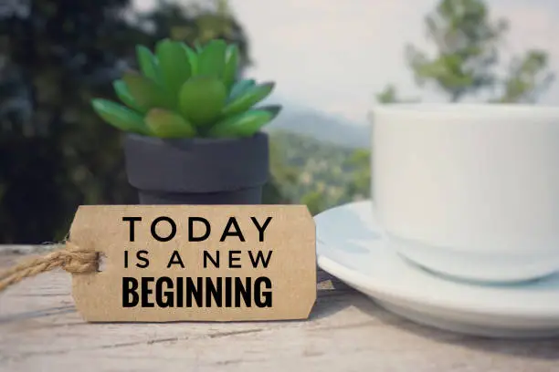 ‘TODAY IS A NEW BEGINNING’ written on a paper tag. Blurred styled background.