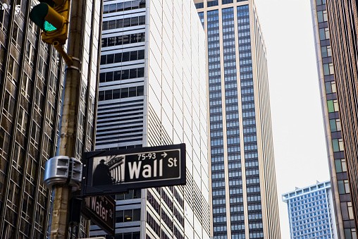 Wall Street sign with a background of skyscrapers in Lower Manhattan, New York City