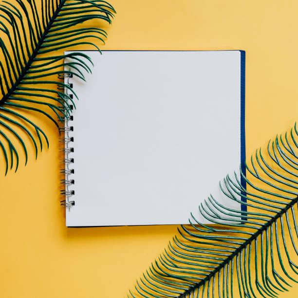 istock Flat lay of minimal workspace blank notebook with green plant on yellow background, spring and summer concept 1059048482