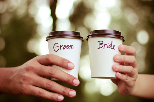 istock Hand holding coffee cup with groom and bride written 1059048678