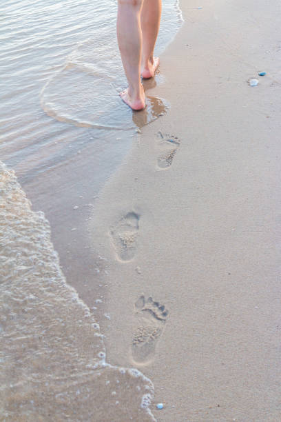 istock Lonely girl walking on the sand with footprints 1059057582