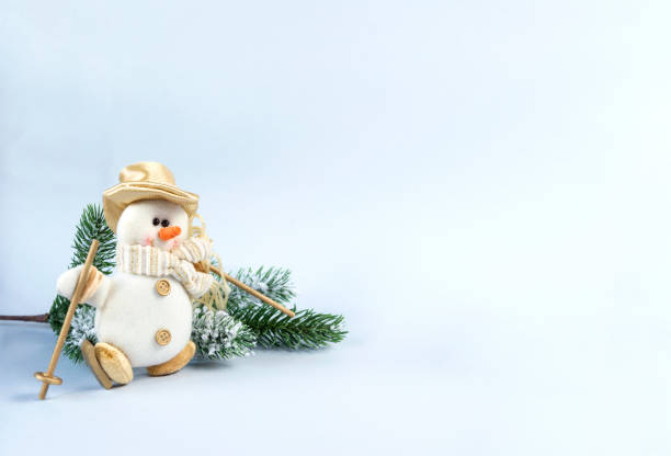 istock toy snowman with hat and scarf, fur-tree branch on a blue background, 1059058092