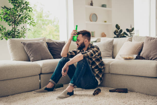 istock People, problem, concept. Brunet bachelor, alcoholic man, sit in mess room puts a cold bottle to your head after hard party 1059059514