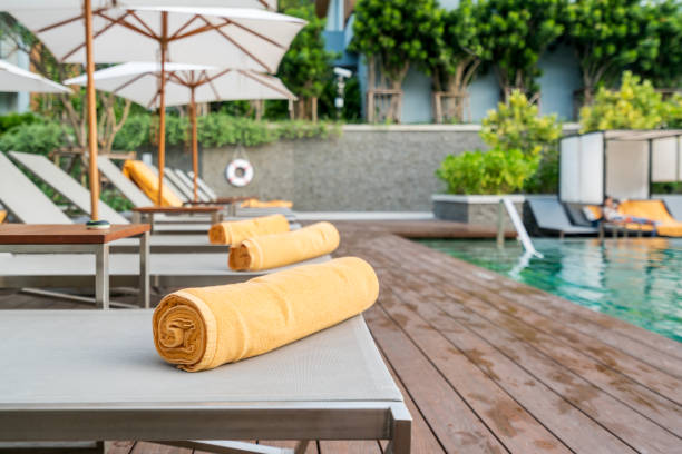 enrollado de toalla naranja sobre un fondo de sol tumbona de piscina en hotel o resort. - poolside fotografías e imágenes de stock