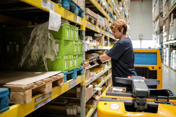 female workhouse worker holding bar code reader against products on shelfs - bar code reader wireless technology computer equipment imagens e fotografias de stock