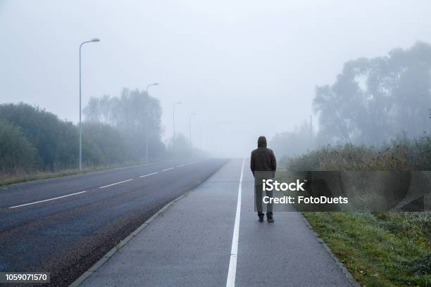 Young Man Alone Walking On Sidewalk In Mist Of Early Morning Foggy Air Go Away Back View Stock Photo - Download Image Now