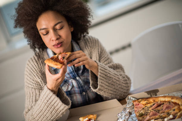 집에서 피자를 먹는 젊은 아프리카계 미국인 여자. - pizza eating african descent lunch 뉴스 사진 이미지