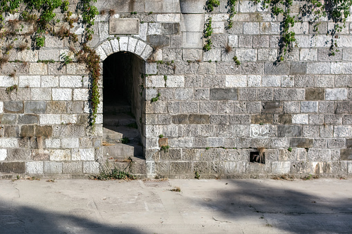 Entrance with steps inside, located in a stone wall on the canal embankment in the Park of the city of Vienna.
