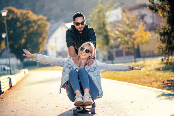 istock Young man pushing his girlfriend on skateboard 1059087092