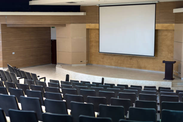 istock Modern seat in empty conference hall with stage and white screen for seminar meeting, Abstract blurred ,Conference business concept 1059088882