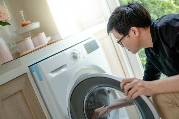 istock Young Asian technician looking into washing machine checking inside. Appliance maintenance in laundry at home. Techonology concept 1059091162