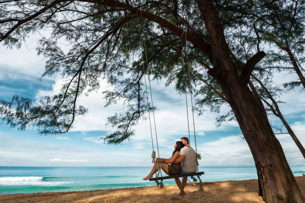 Couple in love on a swing by the sea stock photo