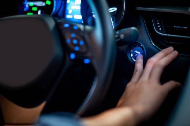 男性ドライバーのプッシュ車のエンジン スタート ストップ ボタンまたは電源点火ボタンによって青い光コンソール ダッシュ ボードで現代の車のステアリング ホイール。自動車産業の自動� - on wheels 写真 ストックフォトと画像