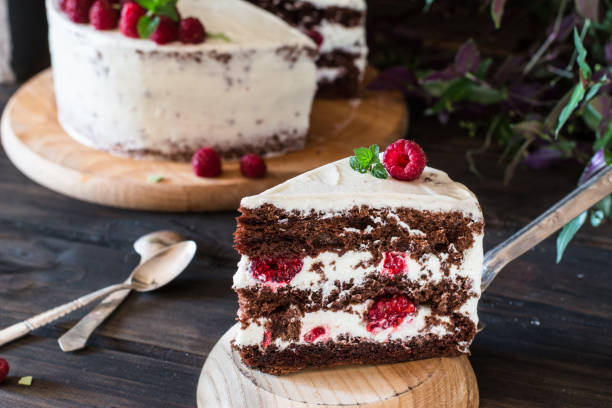 istock Portion of layered creamy fruit cake with in close up view. Raspberry cake with chocolate. Chocolate cake. Mint decoration. Cheesecake on wooden table. Still life of food. Black forest cake 1059094260