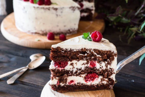 istock Portion of layered creamy fruit cake with in close up view. Raspberry cake with chocolate. Chocolate cake. Mint decoration. Cheesecake on wooden table. Still life of food. Black forest cake 1059094262
