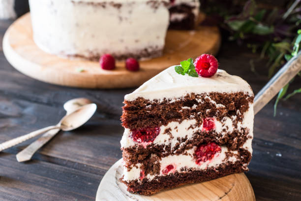 istock Portion of layered creamy fruit cake with in close up view. Raspberry cake with chocolate. Chocolate cake. Mint decoration. Cheesecake on wooden table. Still life of food. Black forest cake 1059094274