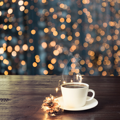 Cup of black coffee on wooden board in cafe. Blurred gold garland as background. Christmas Time. Image for display or montage your products.