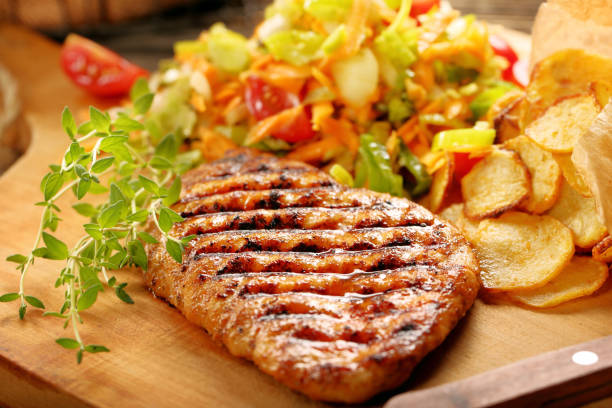 istock Grilled chicken fillet with potato chips and fresh salad 1059096978