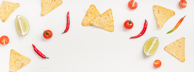 Creative Top view flat lay fresh mexican food ingredients with tortilla nachos chips garlic pepper lime tomatoes on white background copy space. Food preparation cooking concept frame Long wide banner