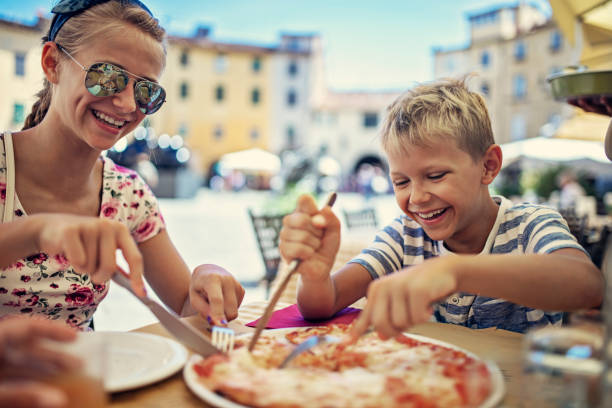 Brother and sister enjoying pizza lunch in Lucca street restaurant Little boy and his sister having lunch with in street restaurant in Lucca  Italy. Family is enjoying a happy meal together. 
Nikon D850 lucca italy stock pictures, royalty-free photos & images