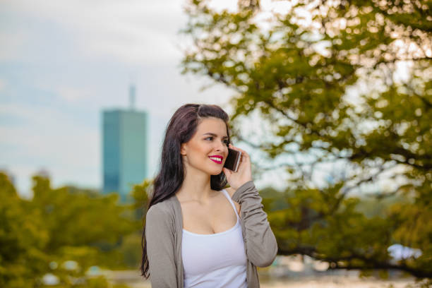 Cute young woman using cellphone in urban surroundings.