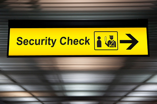 security check sign hanging from airport terminal ceiling