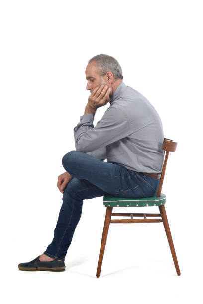 Mature man sitting on chair looking sad over white background