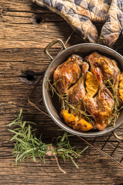 Roasted duck legs in pan with oranges herbs red cabbage and potato pankaces. Roasted duck legs in pan with oranges herbs red cabbage and potato pankaces. confit stock pictures, royalty-free photos & images