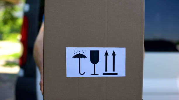 istock Courier in uniform holds box with keep dry fragile this way up signs, service 1059113030