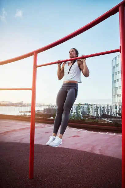 Full length shot of an athletic young woman working out in a calisthenics park in the city