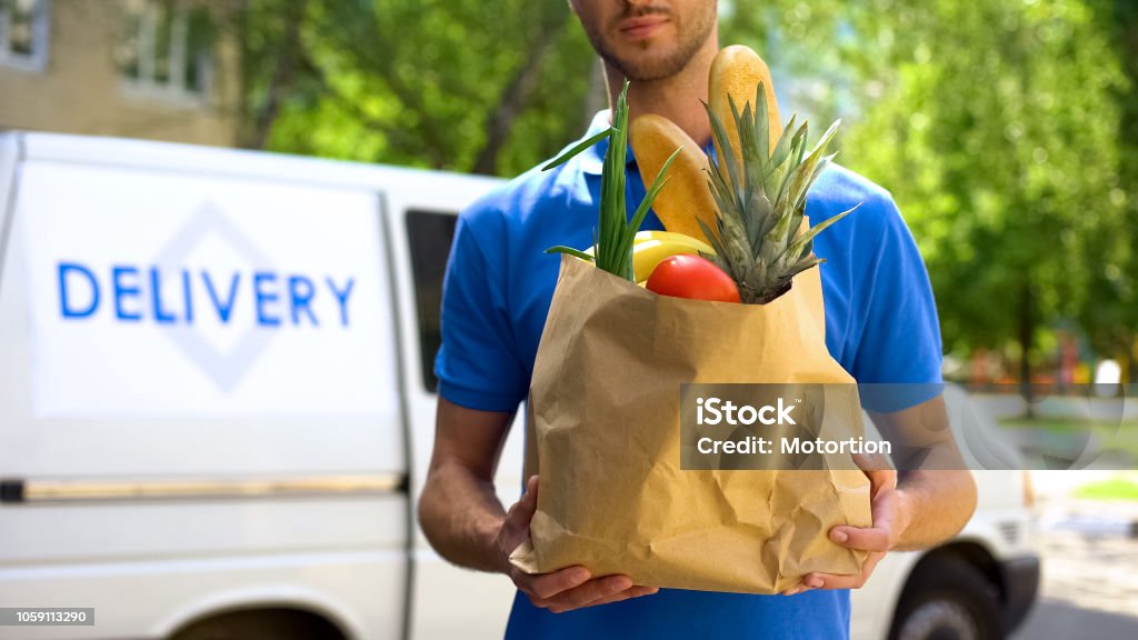 Food delivery service, male worker holding grocery bag, express food order Delivering Stock Photo