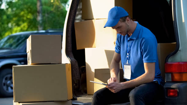 delivery worker checking parcel amount in van, stocktaking report on tablet - delivery van audio imagens e fotografias de stock