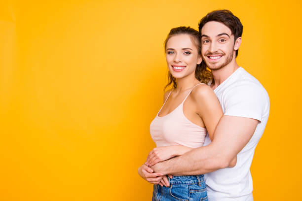 istock Portrait with copyspace empty place of attractive stylish partners hugging looking at camera isolated on vivid yellow background. Trust support idyllic understanding harmony concept 1059116884