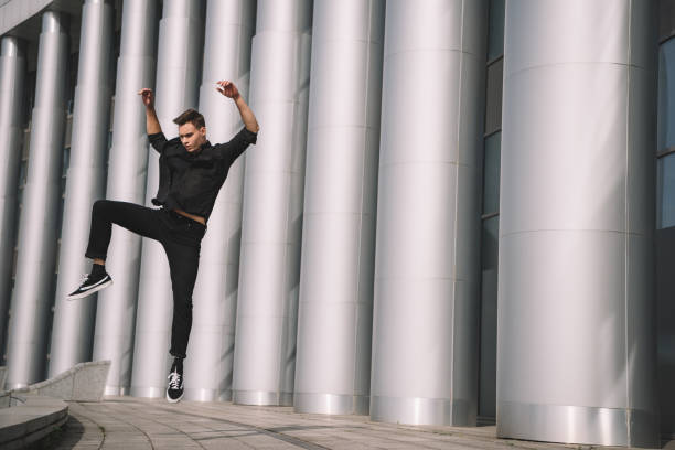 istock handsome young man in black clothes dancing and jumping near columns 1059119122