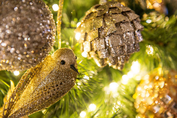 Set of various gold Christmas ornaments including star, heart, pinecone, and traditional round shapes, all hanging from red ribbons. These glittering and shiny decorations bring an elegant and festive touch to holiday décor.