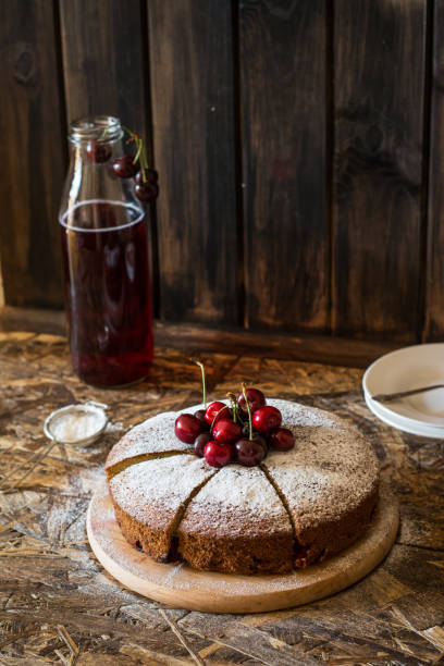 istock Viennese pie with cherry. Traditional cherry pie. Crostata witj berries. Stewed fruit in bottle. Sugar powder on cherry pie lying on wooden desk and wooden table. Homemade bakery. 1059122002