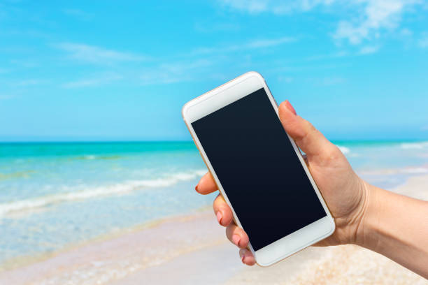istock Beautiful woman's hand using smart phone at beach 1059130576