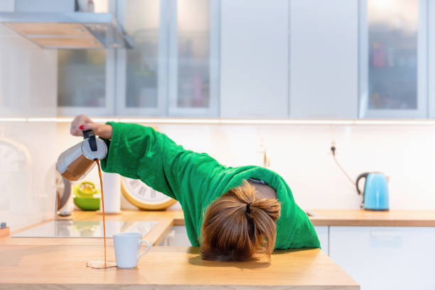 mujer cansada de dormir sobre la mesa en la cocina en el desayuno. intentar beber café por la mañana - cansado fotos fotografías e imágenes de stock