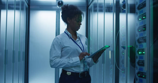 mujer negra con tablet trabajando en sala de servidores - network server black computer network rack fotografías e imágenes de stock