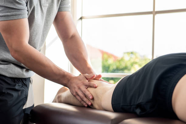piernas dando terapeuta masculino masaje paciente atleta en la cama en la clínica - massaging men swedish culture male fotografías e imágenes de stock