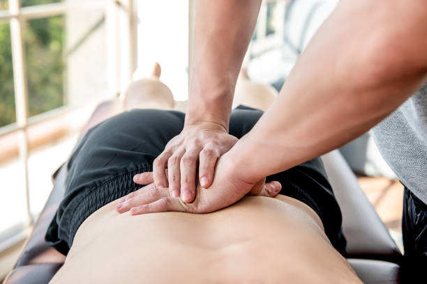 terapeuta dar baje masaje deportivo a paciente masculino de atleta - massaging men swedish culture male fotografías e imágenes de stock