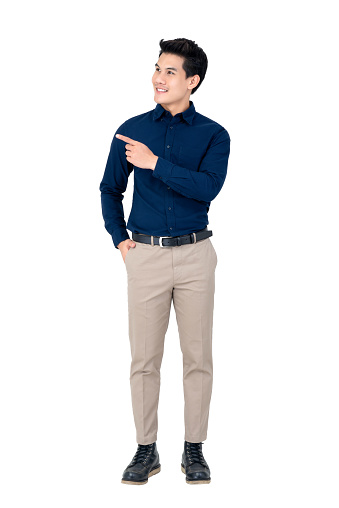 Studio portrait of sophisticated handsome smiling young Asian man wearing semi formal clothing while pointing at space aside