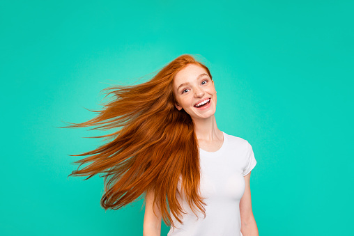 Portrait of careless, carefree lady isolated on vivid teal background turn head and make light, airy hair, white beaming smile