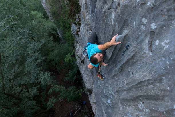 alpinista che sale sulla parete rocciosa - arrampicata su roccia foto e immagini stock