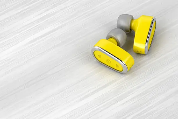 Yellow wireless in-ear headphones on wood table