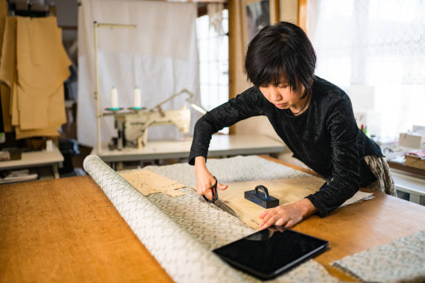 senior woman cutting fabric in her small business textile shop. - independence business women manual worker imagens e fotografias de stock