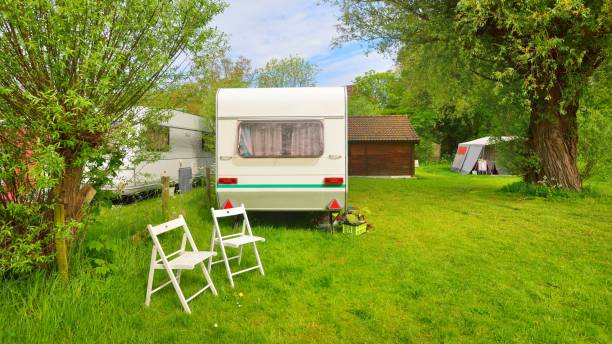 istock Caravan trailer camping on a green lawn under a tree in springtime 1059155786