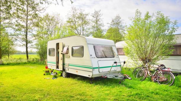 istock Caravan trailer camping on a green lawn under a tree in springtime 1059155796