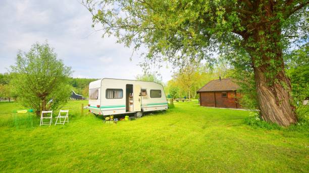 istock Caravan trailer camping on a green lawn under a tree in springtime 1059155798