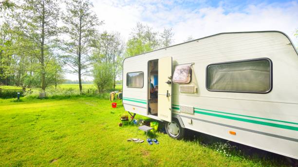 istock Caravan trailer camping on a green lawn under a tree in springtime 1059155806
